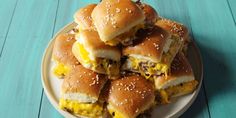 a plate full of cheeseburger sliders on a blue wooden table with sesame seed sprinkles