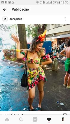 a woman in a colorful dress is dancing on the street with other people behind her