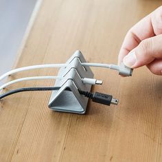 a person is plugging in to an electronic device with two wires and a charger