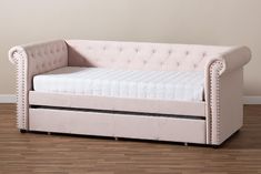 a white couch with a mattress underneath it on the floor next to a wooden floor