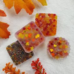 four different colored glass pieces sitting on top of a white towel next to autumn leaves