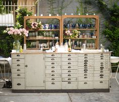 an old dresser with lots of bottles and glasses on it's top is sitting outside