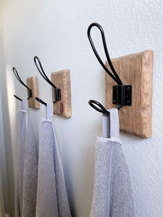 three towels are hanging on the wall with black clips attached to them, and one has a towel hook