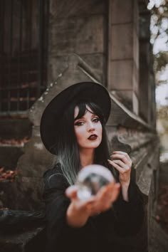 a woman with long black hair wearing a witches hat and holding a glass in her hand