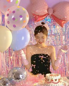 a woman standing in front of a cake surrounded by balloons