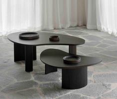 two black tables sitting on top of a stone floor