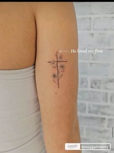 a woman's arm with a cross and flower tattoo on the back of her left arm