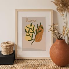 a brown vase sitting on top of a wooden table next to a framed print with the word home