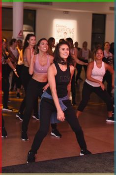 a group of women are dancing in a dance class with one woman holding her leg up and smiling at the camera