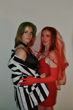 two women dressed up in costumes posing for the camera with one woman wrapped around her