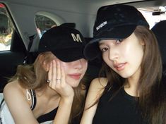 two young women sitting in the back seat of a car, one wearing a black hat