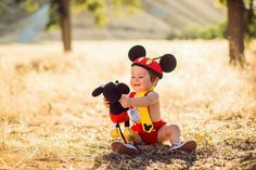 a baby dressed as mickey mouse sitting in the grass