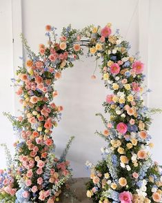 two floral archways are decorated with pink, yellow and blue flowers