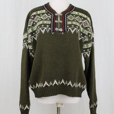 a green sweater with white and red details on the neck, sitting on a mannequin head