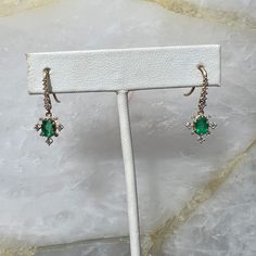 Unique epic hook earrings that add the perfect amount of elegance and sparkle to any look. Featuring stunning oval cut green Emeralds with a radiant diamond halo and diamond studded hooks above the emerald charm for perfect movement. The Vita earrings are sure to be a conversation starter and a treasured heirloom. Emeralds measure 5.8mm x 4mm and total diamond weight is 0.594 carats. Elegant Emerald Diamond Earrings, Green Marquise Earrings For Formal Occasions, Elegant Green Diamond Drop Earrings, Elegant Green Drop Diamond Earrings, Elegant Green Diamond Earrings, Elegant Green Emerald Cut Diamond Earrings, Elegant Green Emerald-cut Diamond Earrings, Green Marquise Earrings In Fine Jewelry Style, Fine Jewelry Green Marquise Earrings