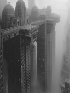 black and white photograph of skyscrapers in the foggy city with tall buildings on either side