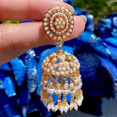 Indulge in the luxury and elegance of our meticulously handcrafted jadau jhumka earrings. The pair features freshwater pearls delicately studded on 925 silver, with 22k gold plating that exudes sophistication. Elevate your style with our unique and exclusive jewelry, designed for those with discerning tastes. Elegant Chandbali Jhumkas With Gota Work, Elegant Jhumkas With Gota Work For Diwali, Elegant Jhumkas With Gota Work, Elegant Gold Jhumkas With Gota Work, Elegant White Meenakari Jhumkas, White Temple Jewelry Pearl Earrings For Diwali, White Temple Jewelry Jhumkas With Cutdana, White Temple Jewelry Style Cutdana Jhumkas, White Temple Jewelry Jhumkas For Eid