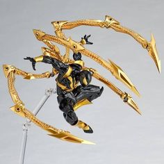 a gold and black action figure with two swords in the foreground, on a gray background