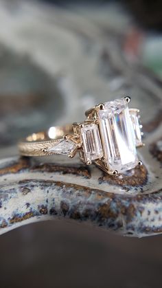 an engagement ring with three baguettes on it sitting on top of a marble slab