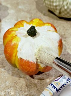 an orange painted with white and yellow paint sitting on top of a counter next to a brush