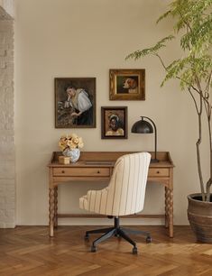 a desk with a chair, potted plant and pictures on the wall