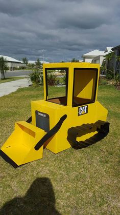 a yellow construction vehicle made out of cardboard sitting in the grass