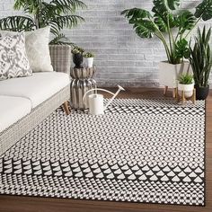 a living room with white couches and potted plants