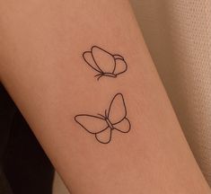 two butterflies tattoo on the arm and one is black with a white outline in it