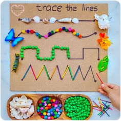 a child's hand is holding up a piece of paper with beads on it