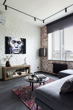 a living room with white brick walls and grey couches next to a coffee table