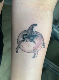 a tattoo on the arm of a person wearing a witches hat and sitting on a dolphin