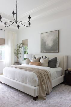 a bedroom with a large bed and a chandelier hanging from the ceiling above it