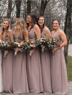 a group of women standing next to each other holding bouquets in their hands and smiling at the camera