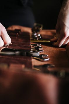 two hands are working on some leather material