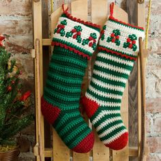 two crocheted christmas stockings hanging from a wooden sleigh