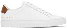 Low-top buffed leather sneakers in white. · Lace-up closure · Padded tongue and collar · Signature series stamp at outer side · Grained leather heel tab · Suede and canvas lining · Textured rubber midsole · Treaded rubber sole Supplier color: White/Tan Line Texture, Common Projects, Classic Sneakers, Leather Sneakers, Leather Heels, Low Top, White Lace, Apparel Accessories, Rubber Sole