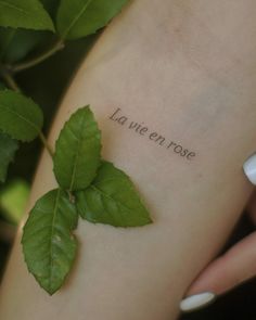 a woman's arm with the words la vie en rose written on it and green leaves