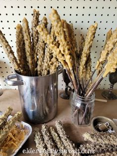 there are some dried flowers in a pot and on the table next to other items