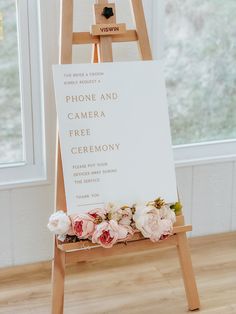 a wooden easel with flowers on it next to a sign