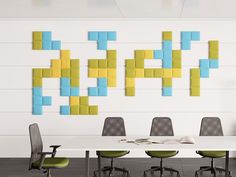 an office with a white table and green chairs in front of a wall that has colorful sticky notes on it