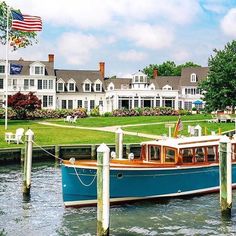 a blue boat is docked in the water next to some houses and an american flag