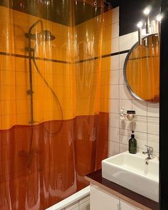 a bathroom with orange shower curtain and white sink