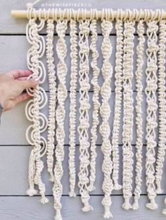 a person is holding up a white crocheted wall hanging