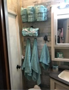 a bathroom with towels hanging on the wall next to a toilet and sink in it