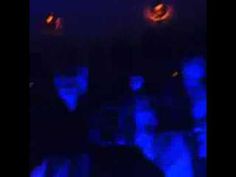 some people are standing in the dark with blue lights on their faces and one person has his head turned to the side