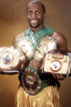 a man holding three different belts in front of his face and smiling at the camera