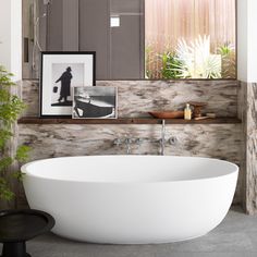 a large white bath tub sitting under a mirror in a bathroom next to a potted plant