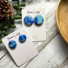 two blue and white earrings sitting on top of a table next to a potted plant