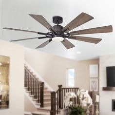 a ceiling fan in the middle of a living room with stairs leading up to it