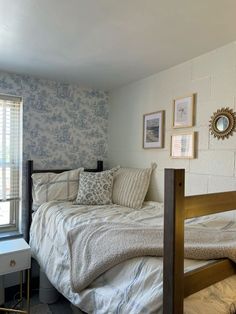 a bed sitting next to a window in a room with blue and white wallpaper